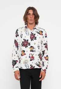 Hvid langsleeve skjorte med et livligt tatoveringsinspireret print med røde roser, fugle, hjerter og hænder; knaplukning, letvægtsmateriale.