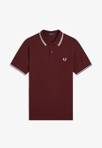 Polo color burdeos con doble raya blanca en el cuello y las mangas, tapeta con dos botones y pequeño logo de corona de laurel en el pecho izquierdo.