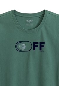 Zielona bawełniana koszulka z okrągłym dekoltem, z granatowym napisem "OFF" oraz grafiką przełącznika w białe i jasnoniebieskie kropki.