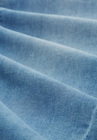Svetlo modra jeans tkanina z mehkobo, rahlim leskom in vidnim tkalskim vzorcem. Tkanina oblikuje nežne, tekoče gube.