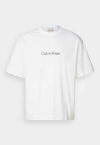 Balta medvilnės marškinėliai su trumpomis rankovėmis, su pilku "Calvin Klein" logotipu, esančiu centriniame krūtinės regione. Klasikin�ė apvalios iškirptės forma, laisvas siluetas.