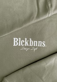 Olijfgroene sweatshirt met een gladde textuur, met een wit geborduurd logo "Blckbnns Design Dept." aan de voorkant.