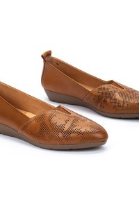 Des chaussures plates en cuir marron avec un bout pointu, présentant des motifs perforés et un petit talon en wedge. Texture lisse avec un design minimaliste.