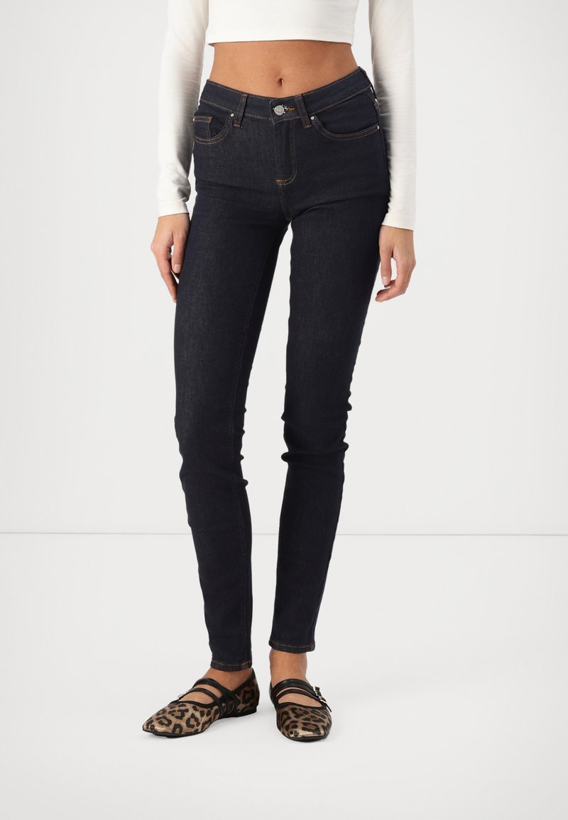 Σκούρο μπλε λεπτά τζιν με ψηλή μέση, πο�υ διαθέτουν πέντε τσέπες και ραφές αντίθετης απόχρωσης, συνδυασμένα με φλατ παπούτσια λεοπάρ.