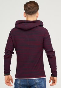 Kapuzensweatshirt mit einem Design aus dunkelmaroonen und marineblauen Streifen, langen Ärmeln und einem strukturierten Strickstoff. Sichtbare Kängurutasche.