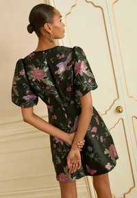 Rochie neagră cu model floral, cu mâneci bufante, având flori roz și păsări brodate. Textură netedă și siluetă ajustată.