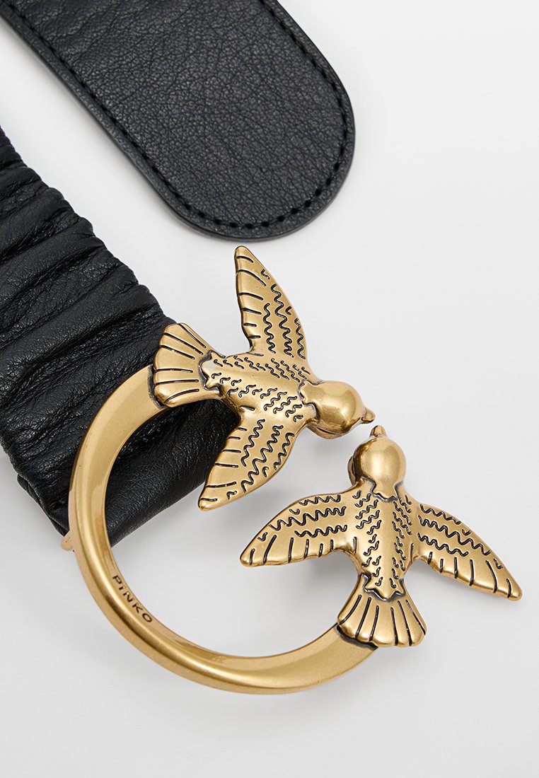 Czarny skórzany pasek z marszczeniami. Złocona klamra ozdobiona stylizowanymi ptakami, z misternie wygrawerowanymi wzorami, w okrągłej ramie.