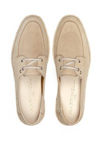 Zapatos de ante beige con acabado texturizado, puntera redonda, diseño de cordones y cordones de color gris claro. Presenta un logotipo sutil en el lateral.
