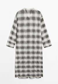 Lange, losvallende jurk met een V-hals, voorzien van een zwart-wit ruitpatroon. Gemaakt van een textuurstof met driekwart mouwen.