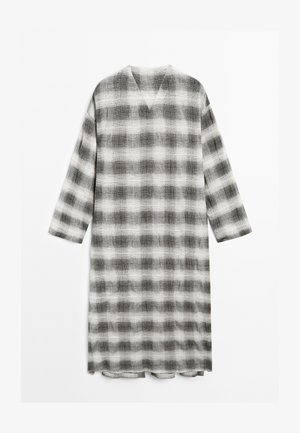 Lång, löst sittande klänning med V-halsringning, prydd med ett svart och vitt rutigt mönster. Tillverkad av strukturerad tyg med trekvartslånga ärmar.