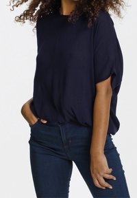 Maglietta blu navy, comoda e realizzata in un tessuto leggero, con scollatura rotonda e maniche corte, abbinata a jeans skinny blu scuro.