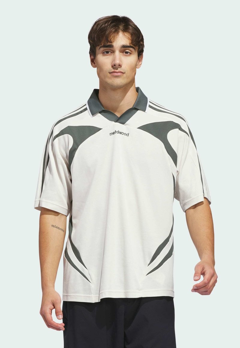 Polo à manches courtes blanc avec des accents gris foncé, doté d'un col contrasté et d'un design graphique dynamique à l'avant. Texture de tissu douce.