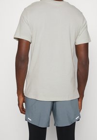 Jasnoszary bawełniany t-shirt z krótkimi rękawami, okrągłym dekoltem i luźnym krojem, w połączeniu z szarymi spodenek sportowych z białym akcentem.