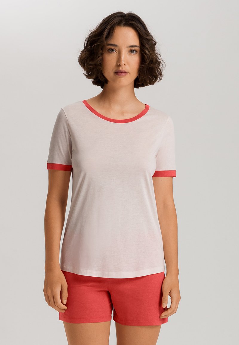 Camiseta de manga corta, de color rosa claro, con ribetes rojos en el cuello y las mangas, combinada con pantalones cortos rojos, fabricados en un tejido suave.