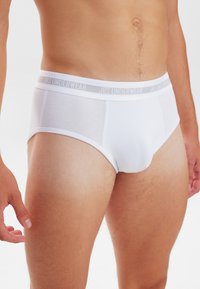 Hvide bomuldsunderbukser med en blød elastisk talje, der bærer "JBS UNDERWEAR" logoet. Klassisk design med en tætsiddende pasform og minimale sømme.