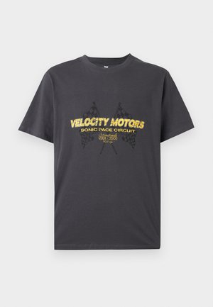 Tricou gri închis cu text galben "Circuitul Sonic de Viteză al Velocity Motors" și un grafic cu steaguri încarcate încrucișate pe față.