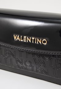 Fekete lakkbőr clutch, amelyen dombornyomott "Valentino" logó, arany színű részletek, sima felület és struktúrált dizájn található.