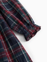 Ναυτικό και κόκκινο καρό ύφασμα με πράσινες και λευκές λεπτομέρειες, με μαζεμένα μανίκια και λεία υφή. Κοντινή απεικόνιση της λεπτομέρειας του μανικιού.