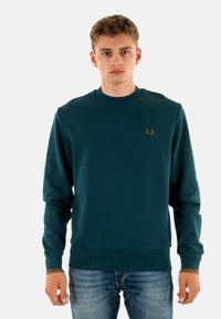 Felpa teal con collo a giro, polsini e orlo a costine, caratterizzata da un piccolo logo ricamato in oro sul petto. Materiale in morbido cotone.