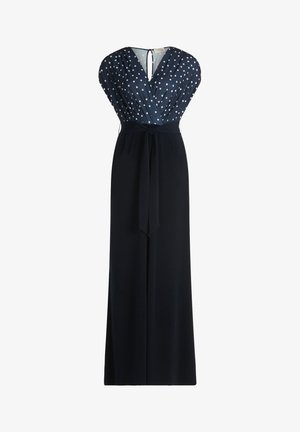 Robe bleu marine avec un haut croisé à pois blancs, sans manches, ceinture nouée à la taille et longue jupe droite.