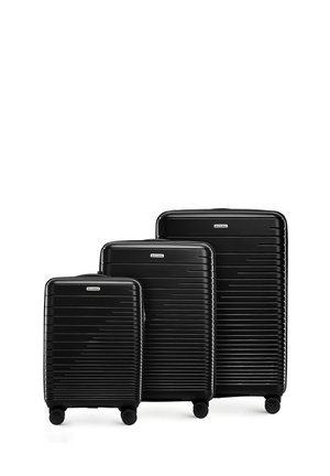 Trzy czarne walizki twarde w różnych rozmiarach. Posiadają paskowy wzór, cztery kółka oraz uchwyty na górze dla łatwej manewrowalności.