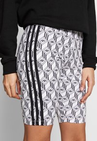 Svart- och vitmönstrade shorts med geometriska mönster, som har tre svarta sidostråkar och ett texturerat material.