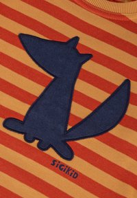 Streifenstoff in Orange und Rot mit einer applizierten Silhouette eines Marineblauen Fuchses und dem Text "SIGIKID" am unteren Rand. Weicher Baumwollstoff.