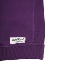 Lila sweatshirt med ribbade manschetter och nederkant. Har en sydd etikett som säger "Band of Rascals." Mjukt tyg, stilen är avslappnad.