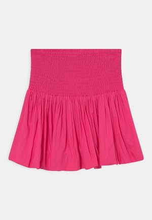 Jupe rose vif avec une large taille smockée et une partie inférieure froncée et évasée sur un fond clair.