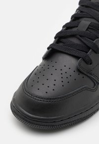 Schwarze Leder-Sneaker mit einer perforierten Zehenkappe, strukturierten Schnürsenkeln und einer flachen Gummisohle mit einem gemusterten Rand und genähten Details.