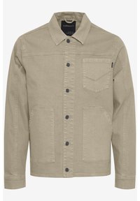 Beige denim jacket with button-up front, pointed collar, two front pockets, and subtle stitching detail on the chest pocket.