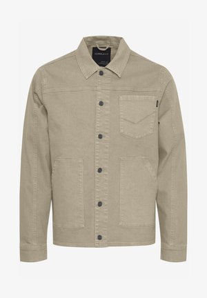 Beige farmerdzseki gombos elülső résszel, hegyes gallérral, két elülső zsebbel és diszkrét varrási részletekkel a mellzsebén.