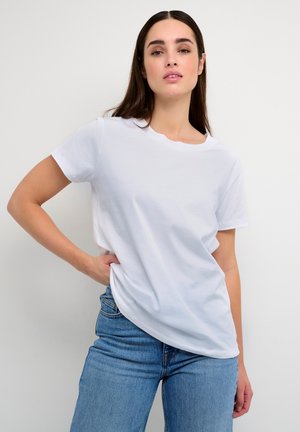 White cotton t-shirt with short sleeves, round neck, relaxed fit. Paired with blue denim jeans, showcasing a casual look.