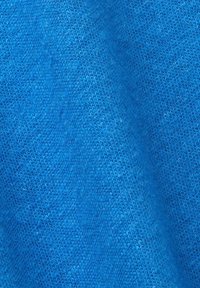Texture de tissu tricoté bleu avec des mailles visibles et des fibres douces, montrant de légers plis et ombres.