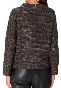Pull marron texturé avec un motif tissé, doté d'une fente au dos et de manches longues, associé à un pantalon en cuir noir élégant.