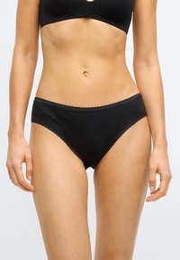 Culotte hipster en coton noir avec une bordure en dentelle à la taille, présentant une texture lisse et une coupe taille mi-haute. Design simple et classique.