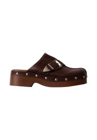 Sabot en cuir marron à enfiler avec une boucle argentée et des clous ronds en métal le long du bord de la semelle, avec un talon plateforme marron massif.