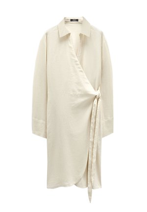 Kremowa koszula zapinana z kołnierzykiem, długimi rękawami i wiązaniem z boku. Miękka faktura, luźny krój i zaokrąglony dół.