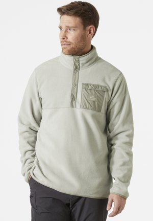 Fleece pullover in light green, featuring a quarter zip, high collar, and a chest pocket with button accents. Soft texture and relaxed fit.