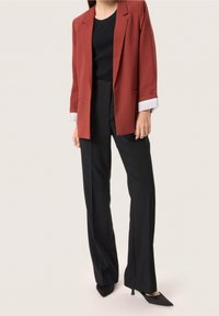 Červený blazer se strukturovaným designem, černý žebrovaný top a černé kalhoty s vysokým pasem. Obsahuje �špičaté podpatky a detail ohrnutého rukávu.