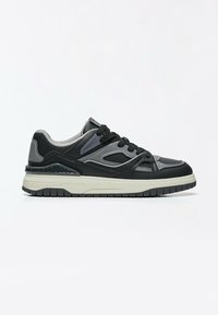 Baskets basses noires et grises avec semelle blanche, lacets noirs et détails en mesh et cuir, vues de profil sur fond blanc.