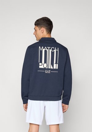 Sweatshirt bleu marine avec un graphique blanc "MATCH POINT" au dos. Présente un design avec col et des poignets et un ourlet côtelés.