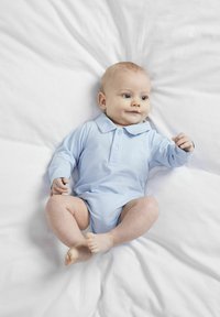 Ljusblå långärmad bodysuit med krage och knappar, bärs av en sittande baby på en vit filt. Slät bomullstyg, neutral pose.