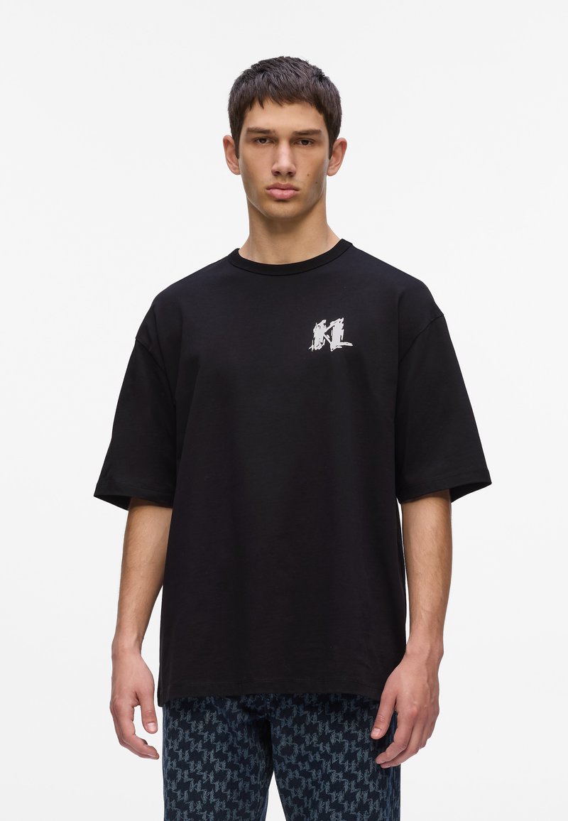 Zwart oversized t-shirt van katoen met een ronde hals en korte mouwen. Bevat een wit grafisch logo op de linkerkant van de borst.