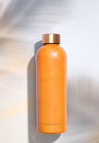 Pomarańczowa stalowa butelka na wodę z błyszczącym wykończeniem, z metalową złotą nakrętką i lśniącymi akcentami. Widoczne wygrawerowane logo.