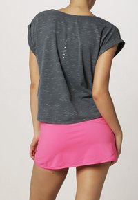 Grå kortärmad topp med lös passform och subtil struktur, parat med en ljusrosa, figurnära skorts. Har dekorativa detaljer på baksidan.