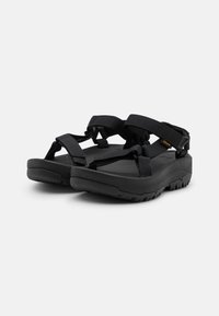 Svarta sandaler med en hållbar gummisula, flera justerbara remmar och en vadderad fotbädd för komfort, designade för utomhusbruk.
