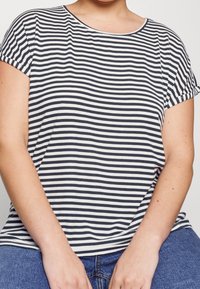 Camiseta de rayas en azul marino y blanco, con escote redondo y mangas cortas enrolladas. Tejido suave con un ajuste relajado.