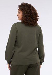 Olivově zelený top s dlouhým rukávem a kulatým výstřihem, vyrobený z jemné látky a s volným střihem. Rukávy mají jemný nabíraný detail.