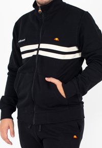 Felpa nera con zip e colletto alto, caratterizzata da strisce bianche sul petto e logo ricamato sul lato sinistro e sul collo.